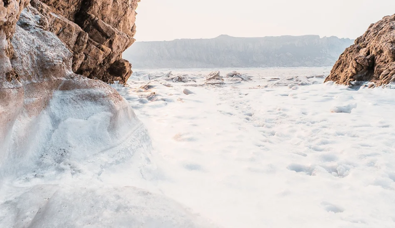 ocean foam splashing between two large rocks